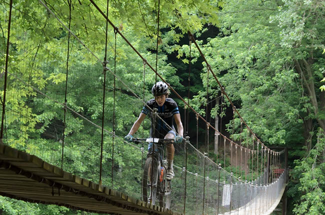 100-mile race winner Dylan Johnson successfully navigates a long suspension bridge. Photo by: Butch Phillips Photography