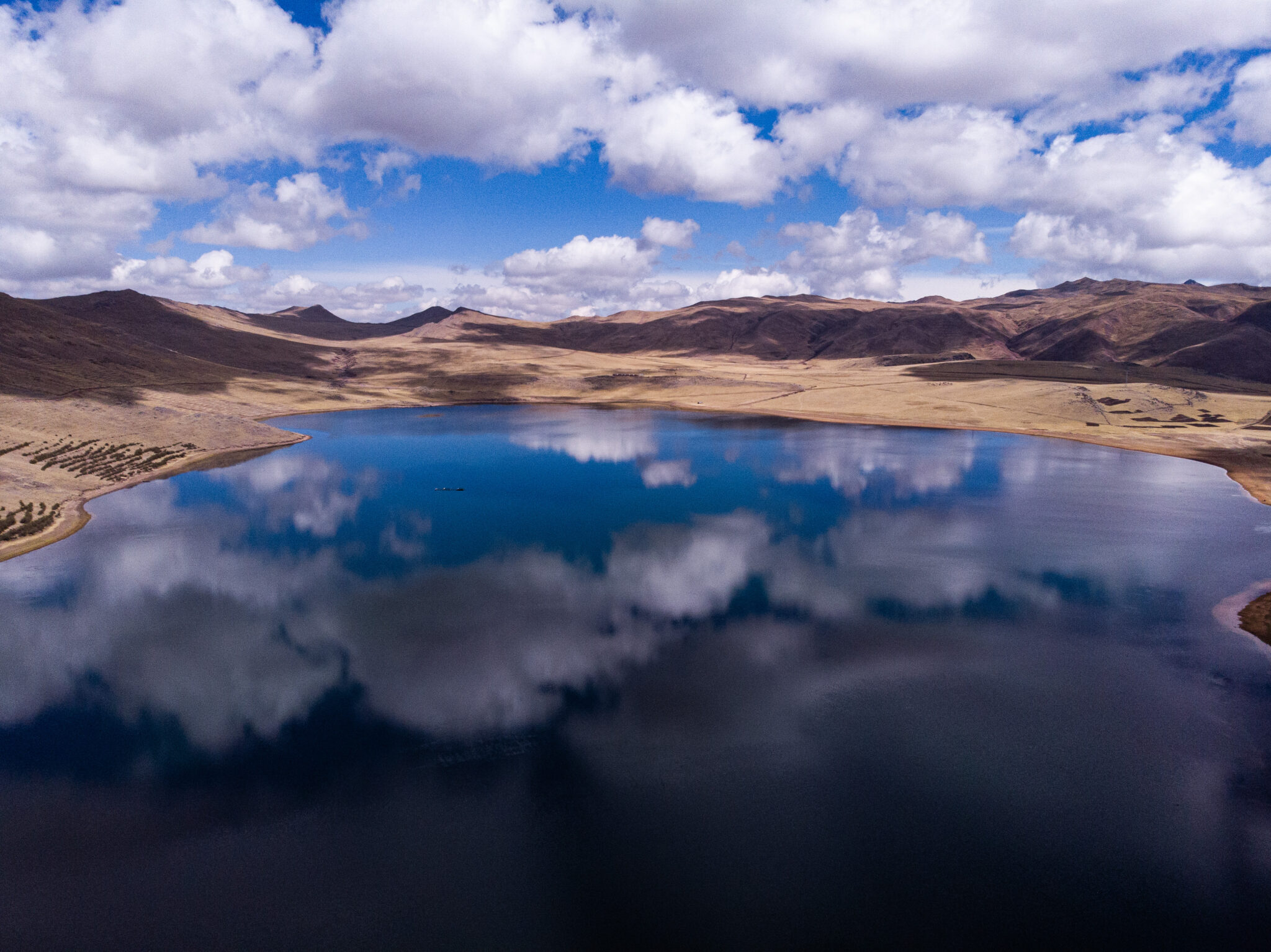 Riders race along a glassy Quirqucha Lake at 13,000 feet above sea level. Photo courtesy of Machu Picchu Epic